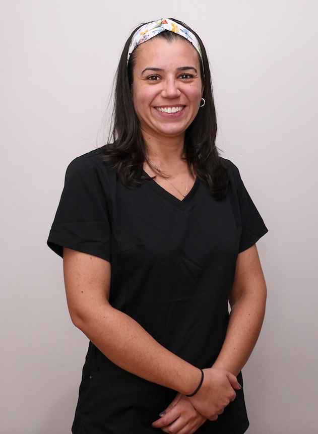 A woman in a black scrub uniform, smiling and posing for the photo.