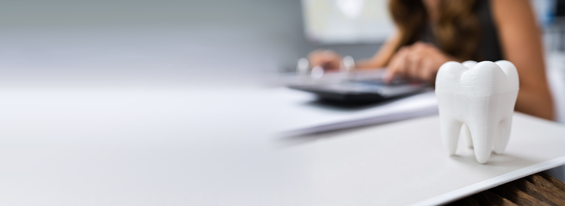 An image of a person working at a desk with a whiteboard, while a small elephant figurine is placed on the desk.