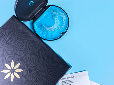 An image featuring a black and white open book next to a blue toothbrush holder with a toothbrush inside, all set against a blue background.
