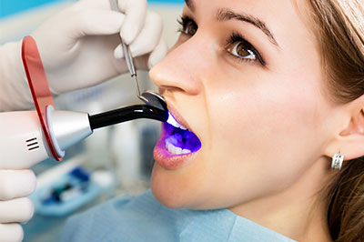 The image shows a person seated in a dental chair with a device attached to their mouth, possibly for dental treatment or cleaning.