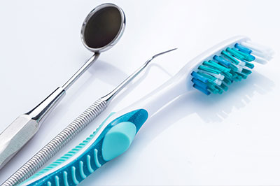 A collection of dental tools, including a toothbrush and a dental mirror, displayed on a white background.