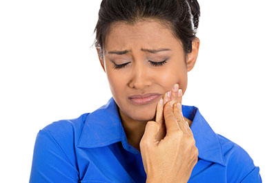 A woman with her eyes closed, holding a toothbrush to her teeth.