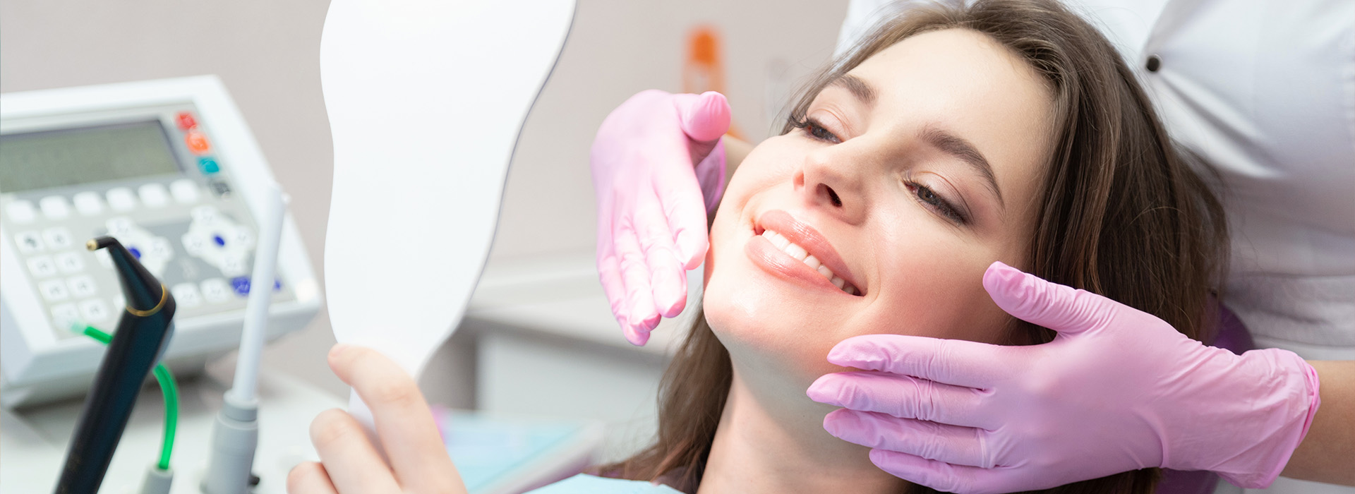 The image shows a woman sitting in a dental chair, receiving dental care from a professional.