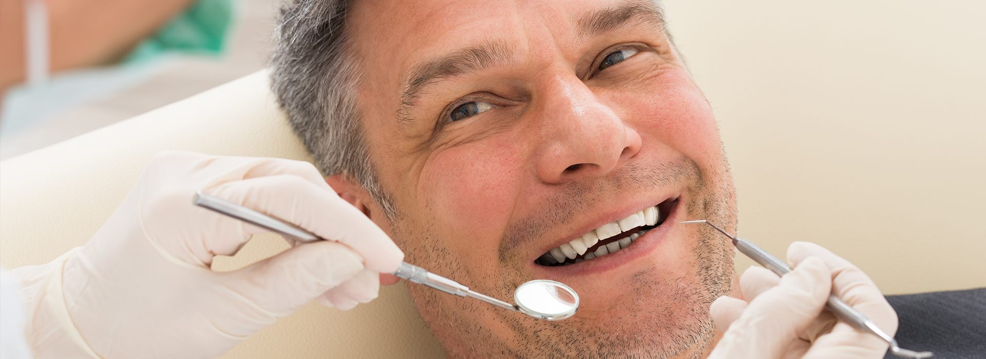 Man sitting in dental chair with mouth open, receiving dental care.