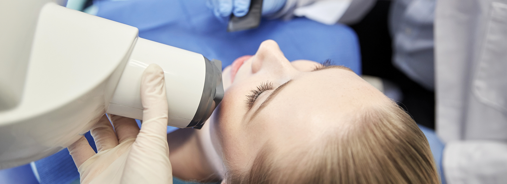 A person receiving a dental implant, with a dentist using a microscope to guide the procedure.