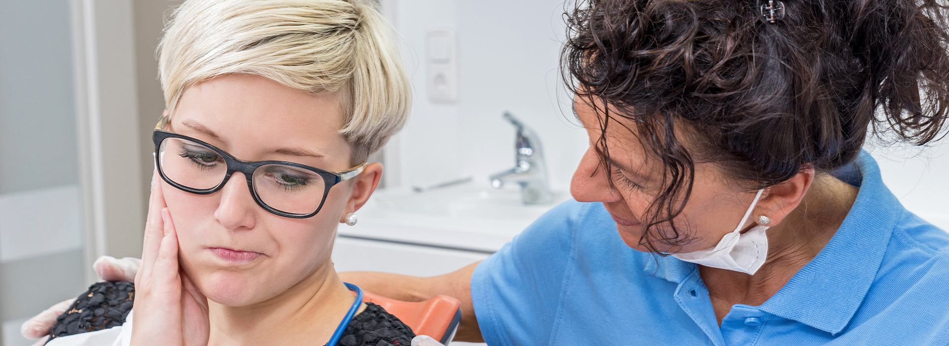 A woman is getting her teeth cleaned by a dental hygienist.