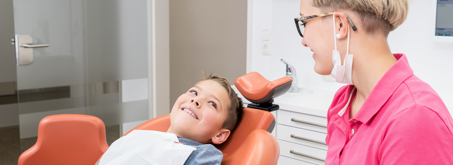 A dental professional assisting a patient in a modern dental office.