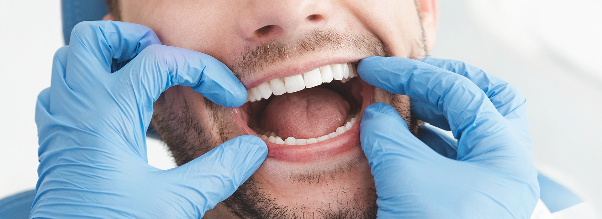 The image features a man wearing a surgical mask and gloves, with his mouth open, likely in the process of speaking or examining something.