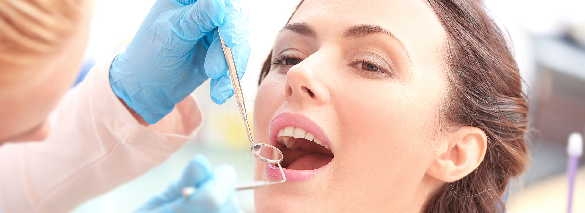 A woman receiving dental care, with a dental hygienist performing the procedure.