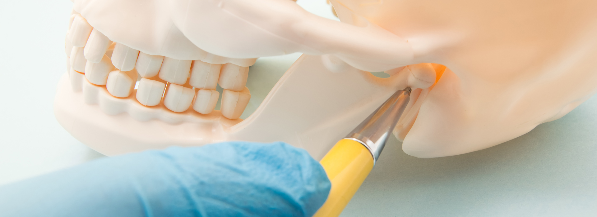 A close-up of a dental procedure, with a tooth being prepared for implantation, featuring a dentist s hand holding a drill and a syringe with yellow liquid.