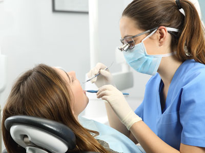 Dental hygienist attending to a patient in a dental chair.